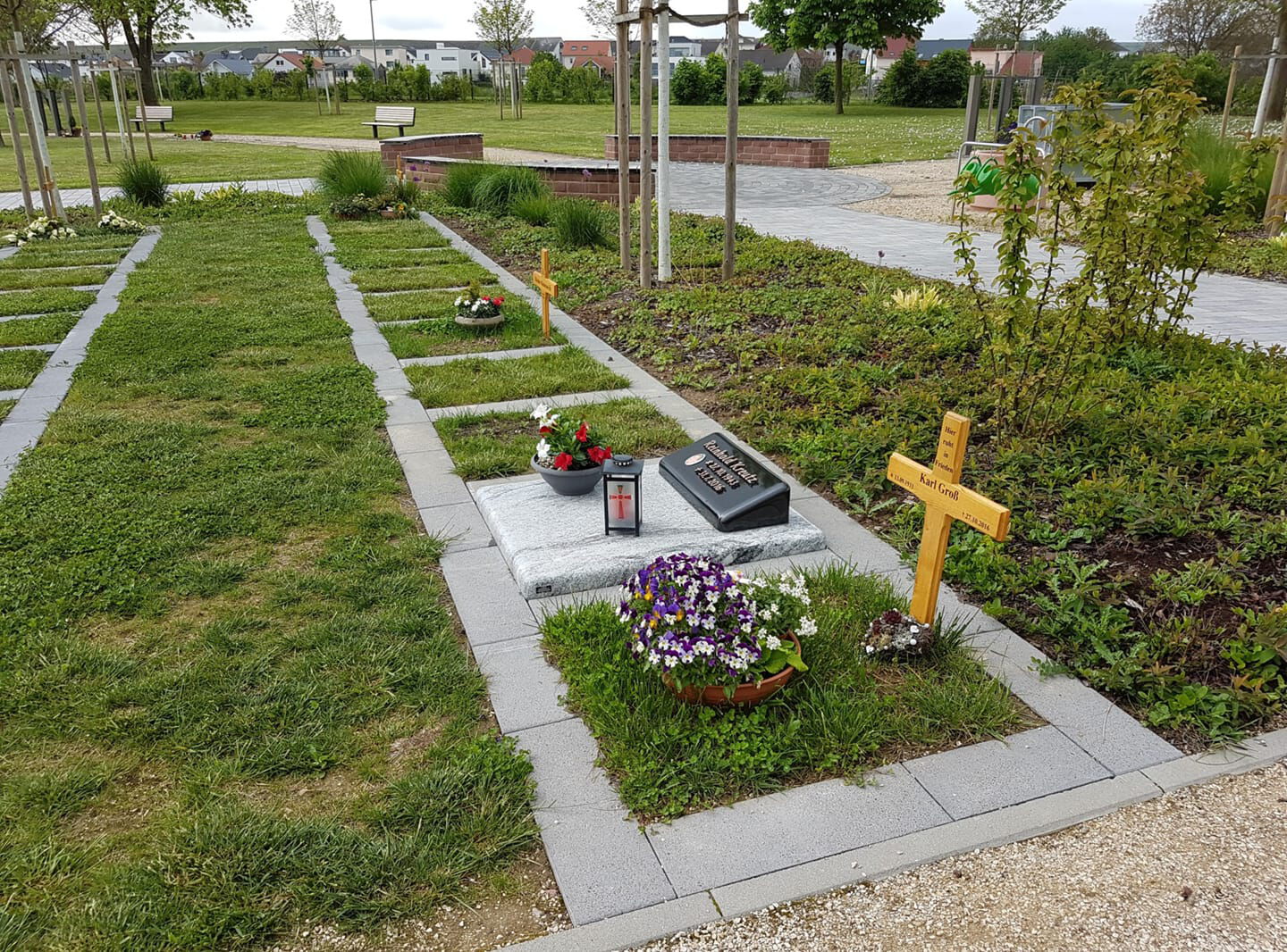 Friedhofsgräber mit Gras bewachsen, Blumen und Bäume