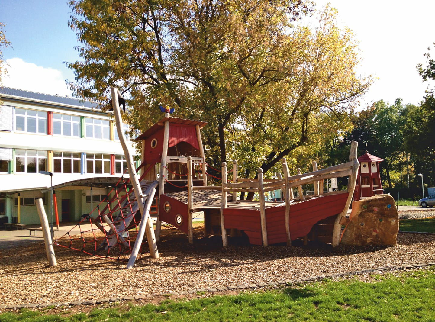 Holzspielschiff vor einer Schule