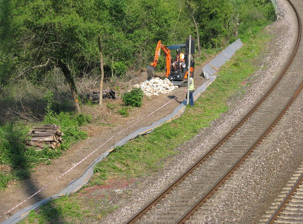 Am Wegrand der Bahngleisen steht ein Bagger