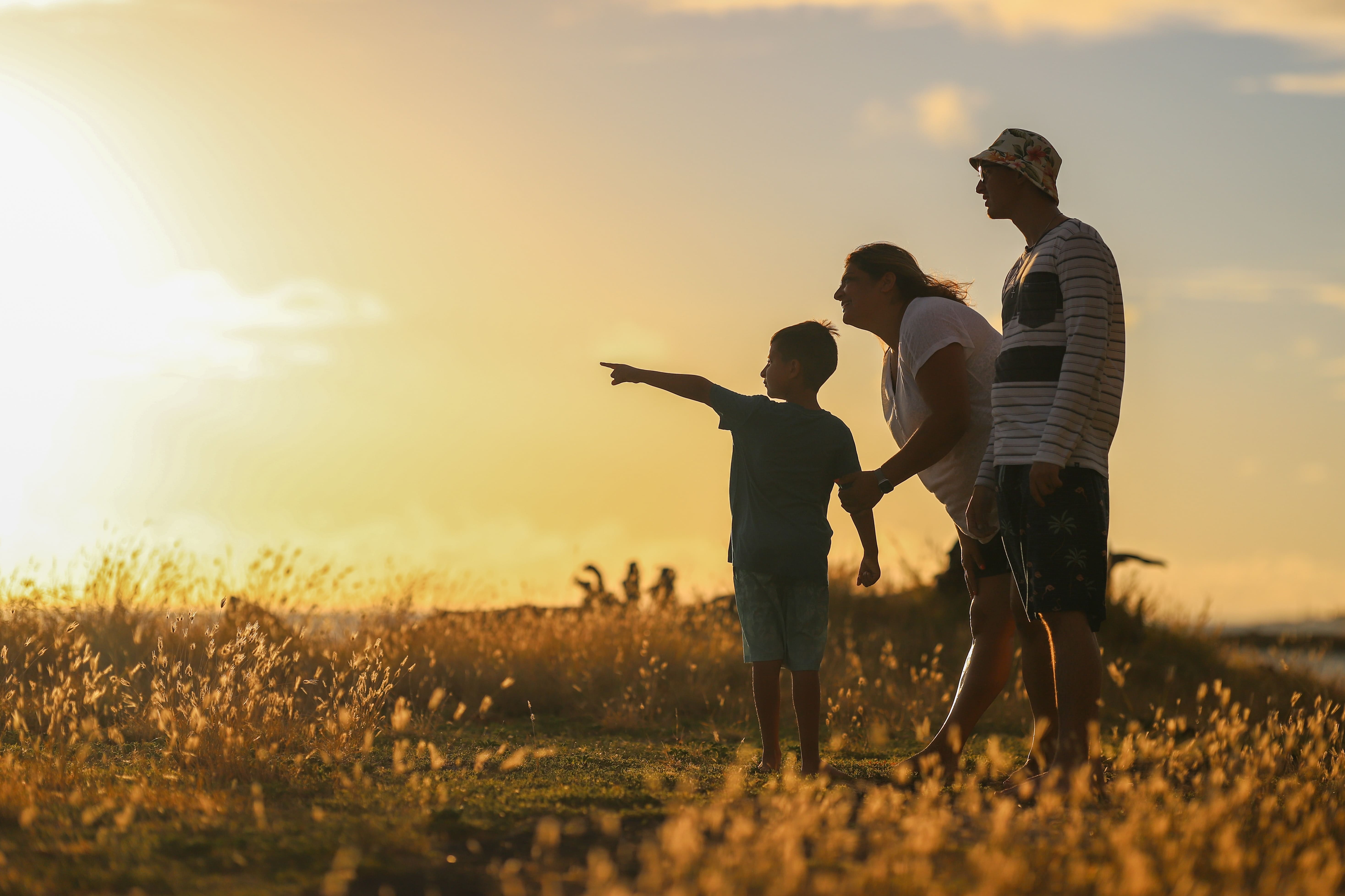 Familie, Mutter, Vater und ein Kind auf dem Feld bei Sonnenuntergang